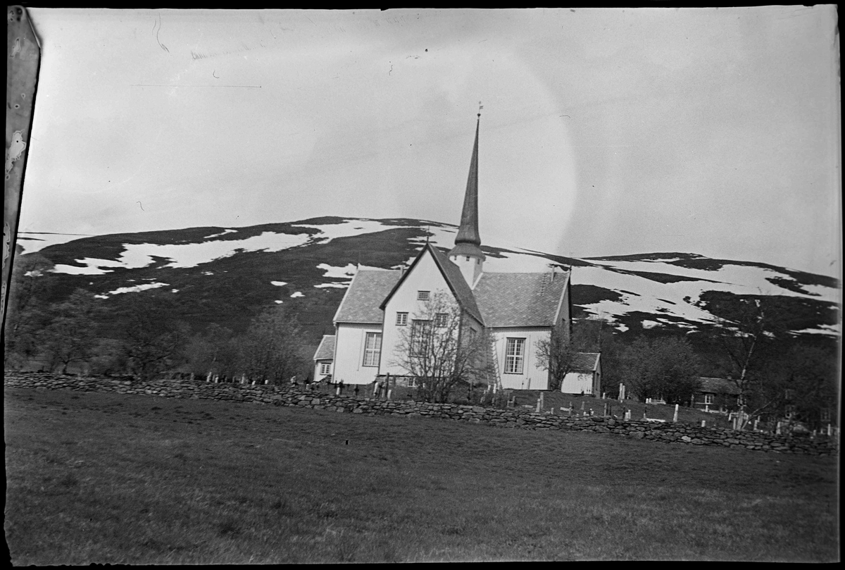 Oppdal kirke med Vangslia i bakgrunnen. Oppdal prestegård er synlig til høyre, bak trærne.
