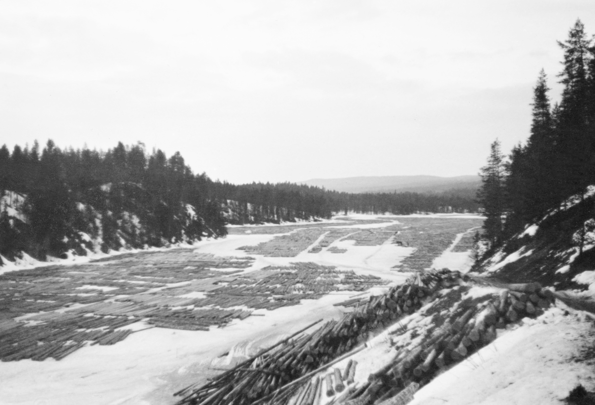 Tømmertillegging på Vesle-Osen, i Søre Osen i Trysil kommune i Hedmark. Fotografiet skal være tatt vinteren 1938. Det viser hvordan et tømmerparti var lagt i såkalte flakvelter på den snødekte isflata. Flakveltene besto av ett lag tømmerstokker som lå parallelt, men vinkelrett på to underlagsstokker. Underlagsstokkene skulle forebygge at tømmeret frøs ned i is og ble altfor fuktmettete etter eventuelle perioder med overvann. Fordelen ved denne tilleggingsmåten var at tømmeret ble veldig lett tilgjengelig for måling og merking. Her var det lett å se og kvalitetsvurdere hver enkelt stokk, med påfølgende «klaving» (diametermåling) og påslåing av kjøpermerker. Stokkene i flakveltene skulle ligge med de lengdemålene skogsarbeiderne hadde hogd på med romertall under apteringa oppovervendt, for å lette målernes arbeid. For å være noenlunde sikker på at tømmeret ikke ble altfor nedsnødd og nediset skulle det helst ikke legges tømmer i flakvelter for tidlig på vinteren. Til høyre i forgrunnen ser vi hvordan tømmer var blitt veltet av sledene fra en tømmerveg i en bratt skråning hvor det etter hvert kunne rulles ned mot strandlinja.