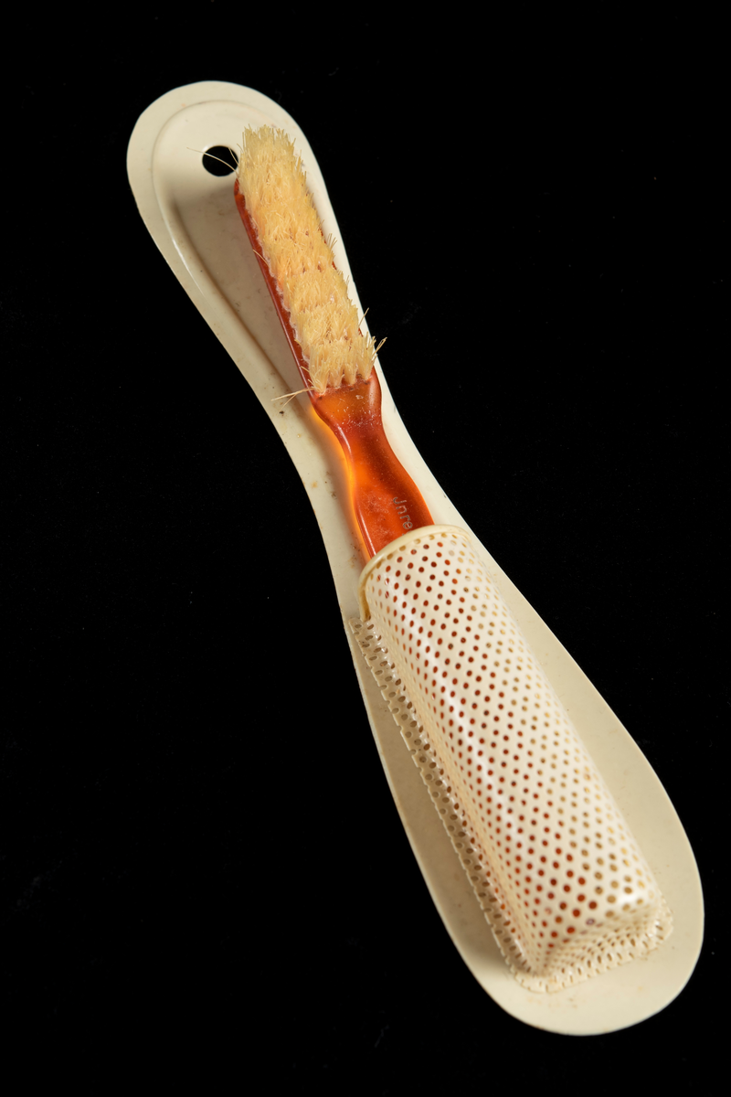 Rödbrun/orange tandborste med tillhörande vit hållare.