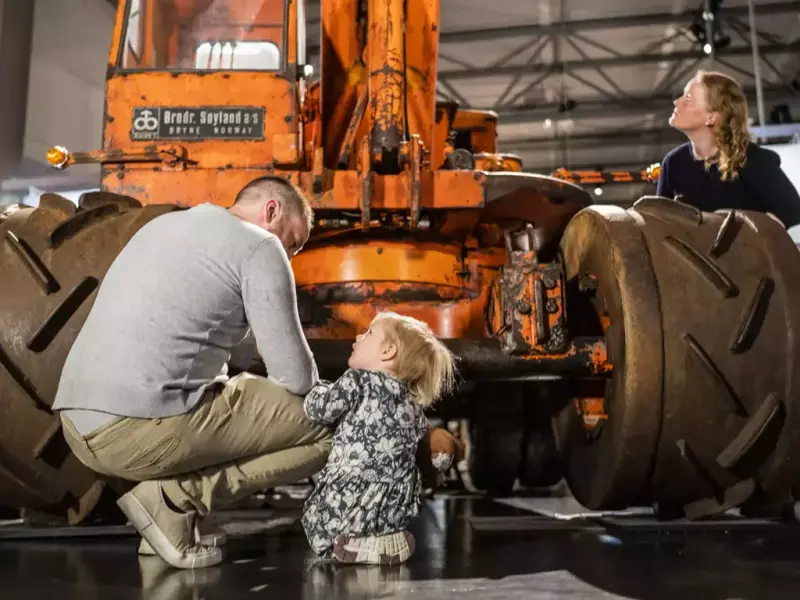 Bildet viser en familie ved en Brøyt-gravemaskin i en utstilling på Norsk vegmuseum.