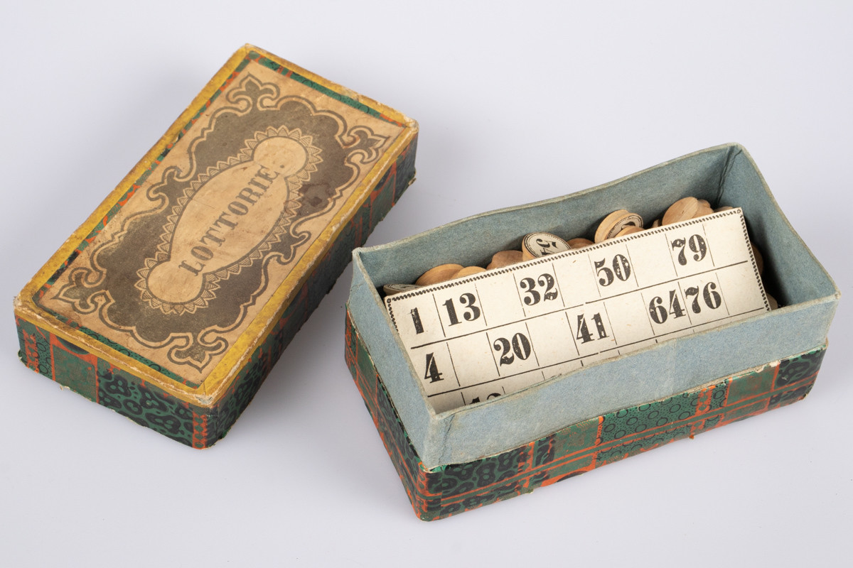 Eske i kartong med brikker og kort med tall på for å spille lotteri eller bingo