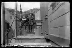 To gutter sitter på benken utenfor inngangen til Strandgaten