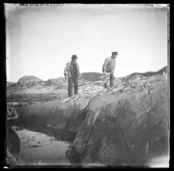To menn jobber med klippfisk som er lagt ut på svaberget