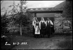 Kvinner i bunad ved porten til Lom kirke