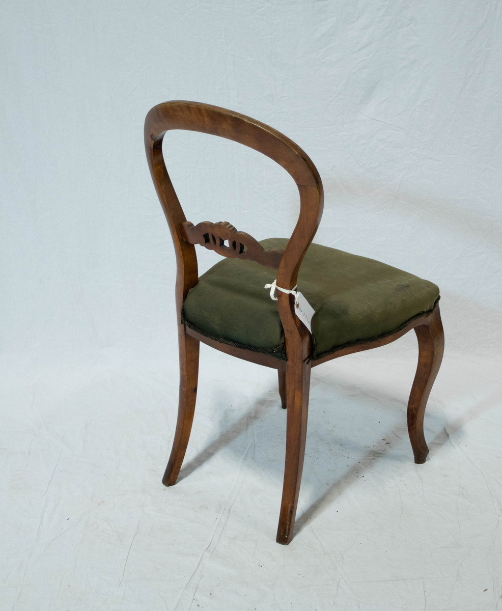 Stol av tre med sete trekt i tekstil. Stolens rygg dannes av en glatt hesteskoformet bue som like over setet gjør en liten knekk utover og så går jevnt over i de nedad bakoverskrånende bakben. I ryggen er det en tverrsprosse med skåren dekorasjon bestående av to løkkeformede blad som er forbundet med en ring. Stolen har S-svungne, nedad avsmalnende forben. Setet er trapesformet med en frontsarg som har buet underkant. Setet er stoppet over spiralfjærer.