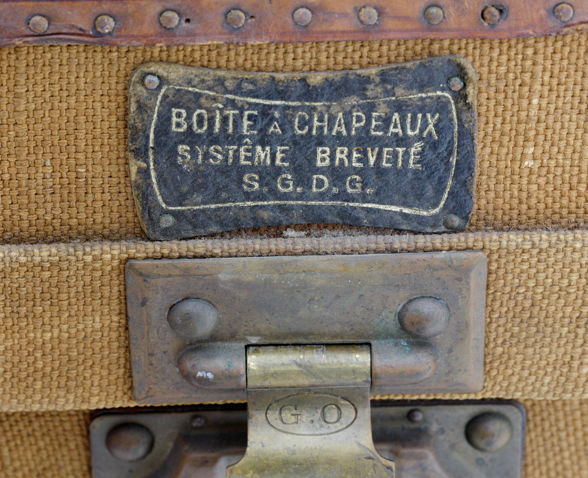 Koffert med initialerna C.M med mörkbruna bokstäver på kortändarna