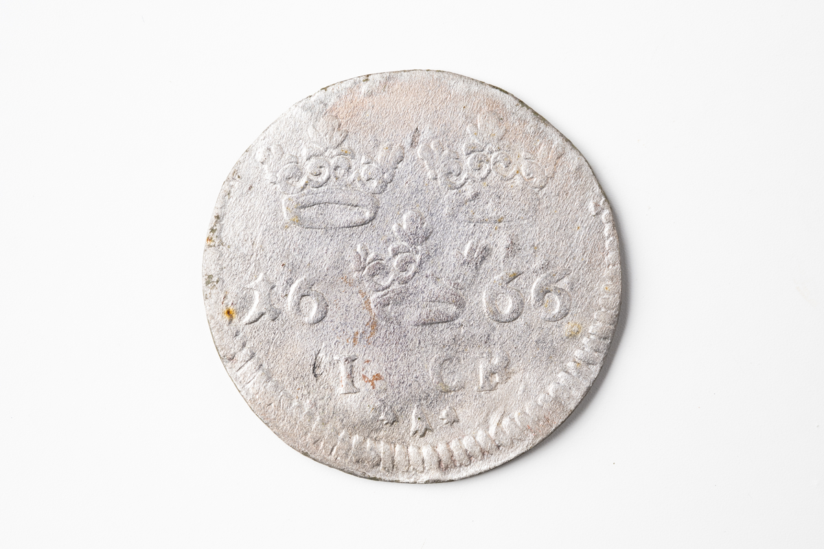 Ett silvermynd, 1 öre, Karl XI, 1666, Stockholm. Metalldetektorfynd i matjorden öster om hus 9006.