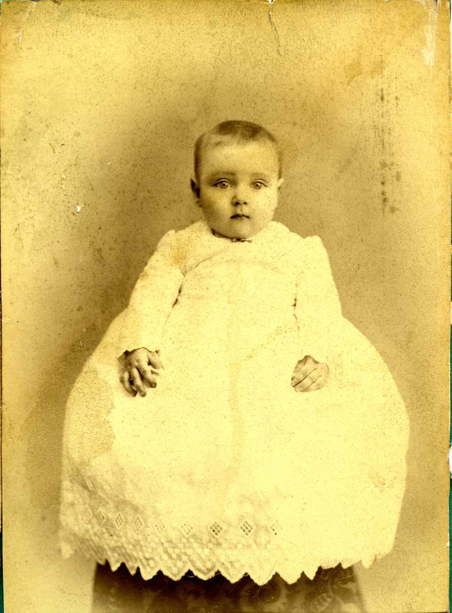 Portrett av sønn til Helge Husemoen i hvit kjole.
