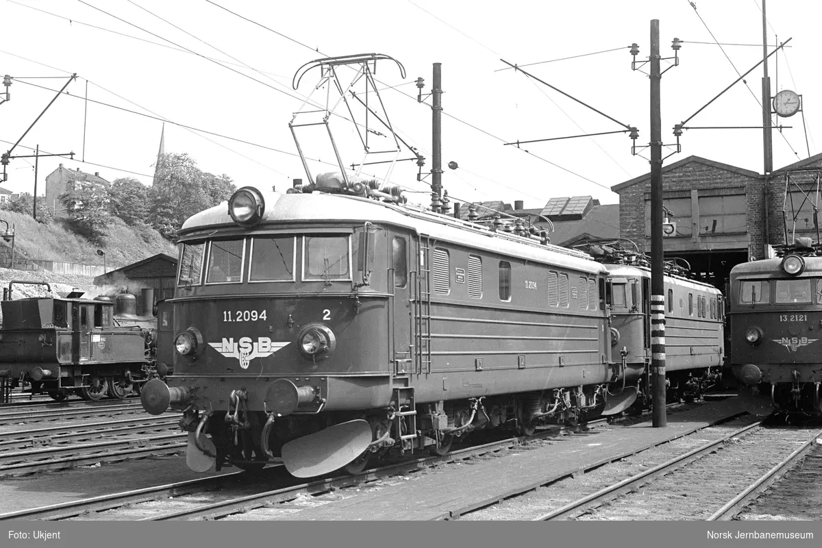 Elektrisk lokomotiv El 11 2094 utenfor Gamlestallen i Lodalen i Oslo. Bak til venstre damplokomotiv type 23b nr. 442, til høyre elektrisk lokomotiv El 13 2121