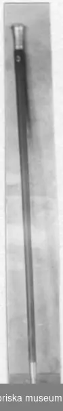Käpp av trä med silverknopp. Silverknoppen är dekorerad med växtornament och märkt i nederkant "JJ Köinge", på sidan "BBS 1778".