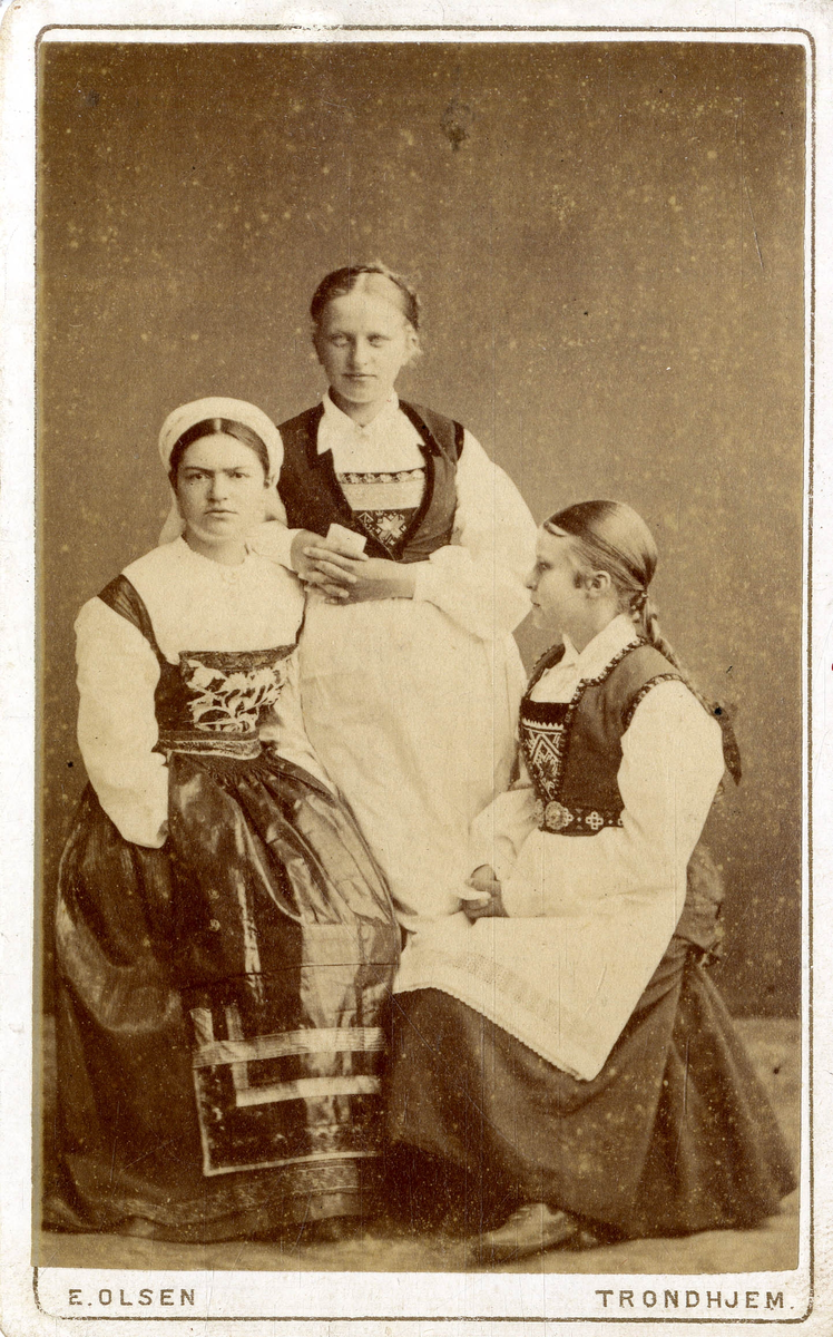 Gruppeportrett. 3 unge kvinner i bunad.