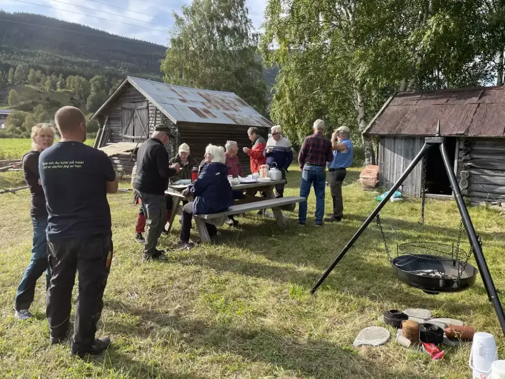 Gruppe mennesker samlet på et tun med benker og bålpanne.