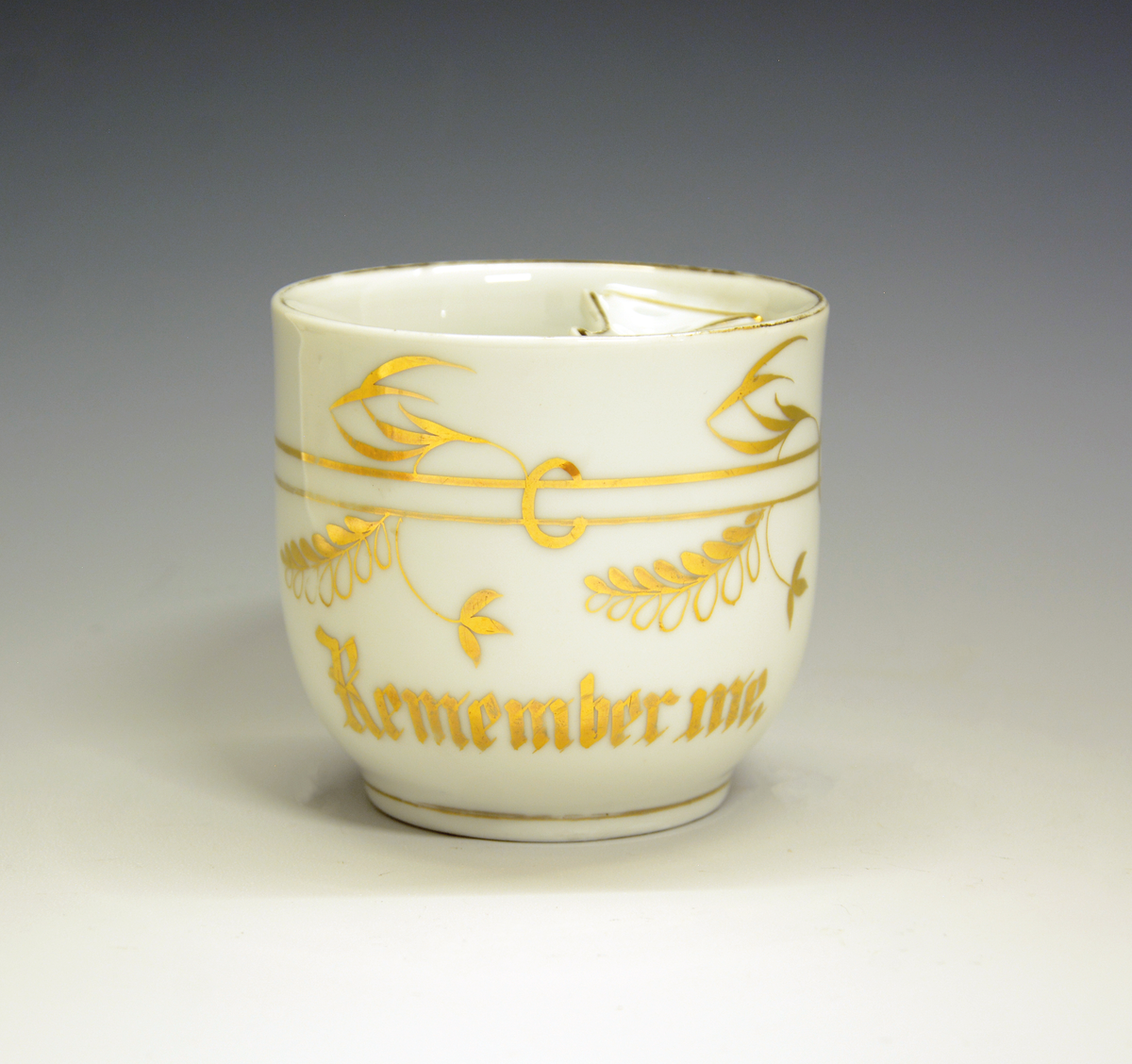Bartekopp av porselen, hvit med gulldekor. Inskripsjon i gull: "Remember me".