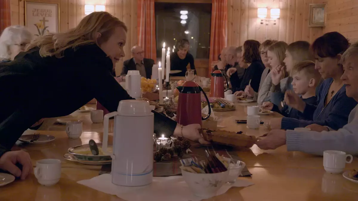 Et bilde av en fest, fra dokumentarfilmen "Without Them I am Lost". Mange mennesker fra ulike generasjoner sitter rundt et bord og spiser sammen.