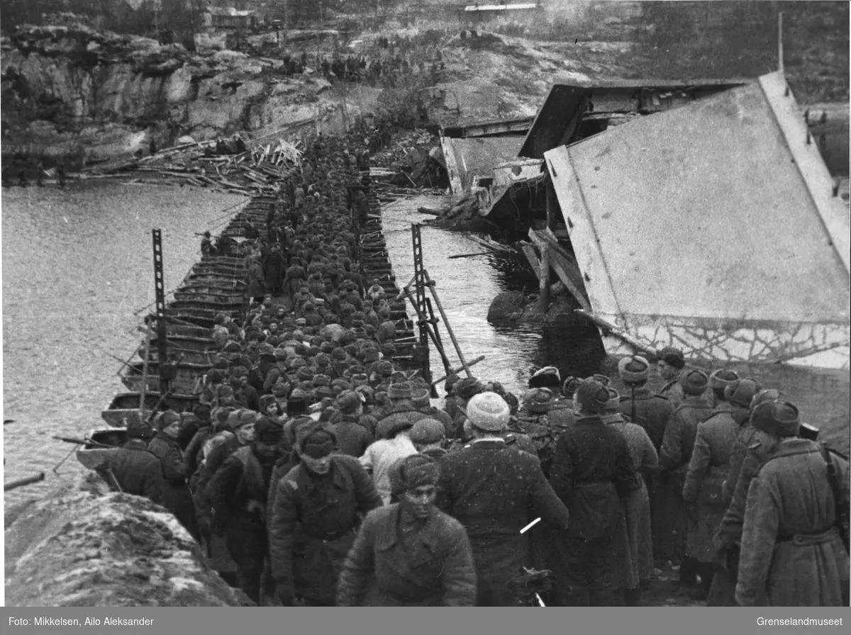 Sovjetiske soldater krysser Pasvikelva over en improviser bru ved siden av den sprengte brua ved Nyrud. Hendelsen fant sted i Pasvikdalen i Sør-Varanger kommune, høsten 1944.  