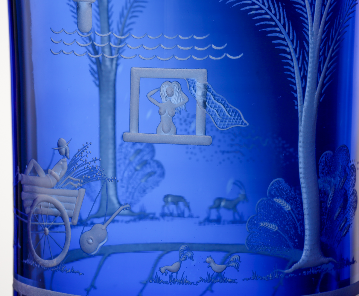 Formgivare: Gunnar Cyrén. Vas med bägarform med blå fond. På livet graverad dekor föreställande scener ur visan
"Oxdragarsång" av Evert Taube.