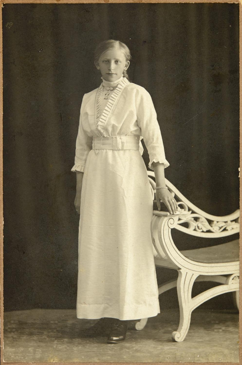 Leirfjord, Leland. Portrett av Ragna Leland (Ragna Olsen). Antatt som konformant i hvit sid kjole og smykker.

Mormor til Kirsti, Marie Leland (jordmor i Leirfjord) var fra Træna.