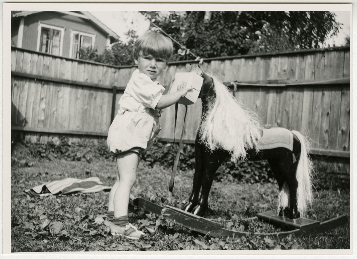 Tor Åge Bringsværd som leker med gyngehest i hagen i sitt barndomshjem i 1942