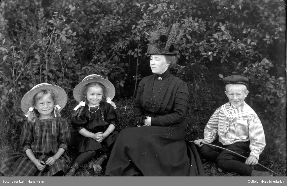 Fotografens kone og barn under bladkronene, ca 1912-1914.
Fra venstre: Ingertha Lauritzen, Solveig Elvira Lauritzen, Lagertha Marie Larsen og Robert William Lauritzen med en kjepp eller fiskestang i hendene.