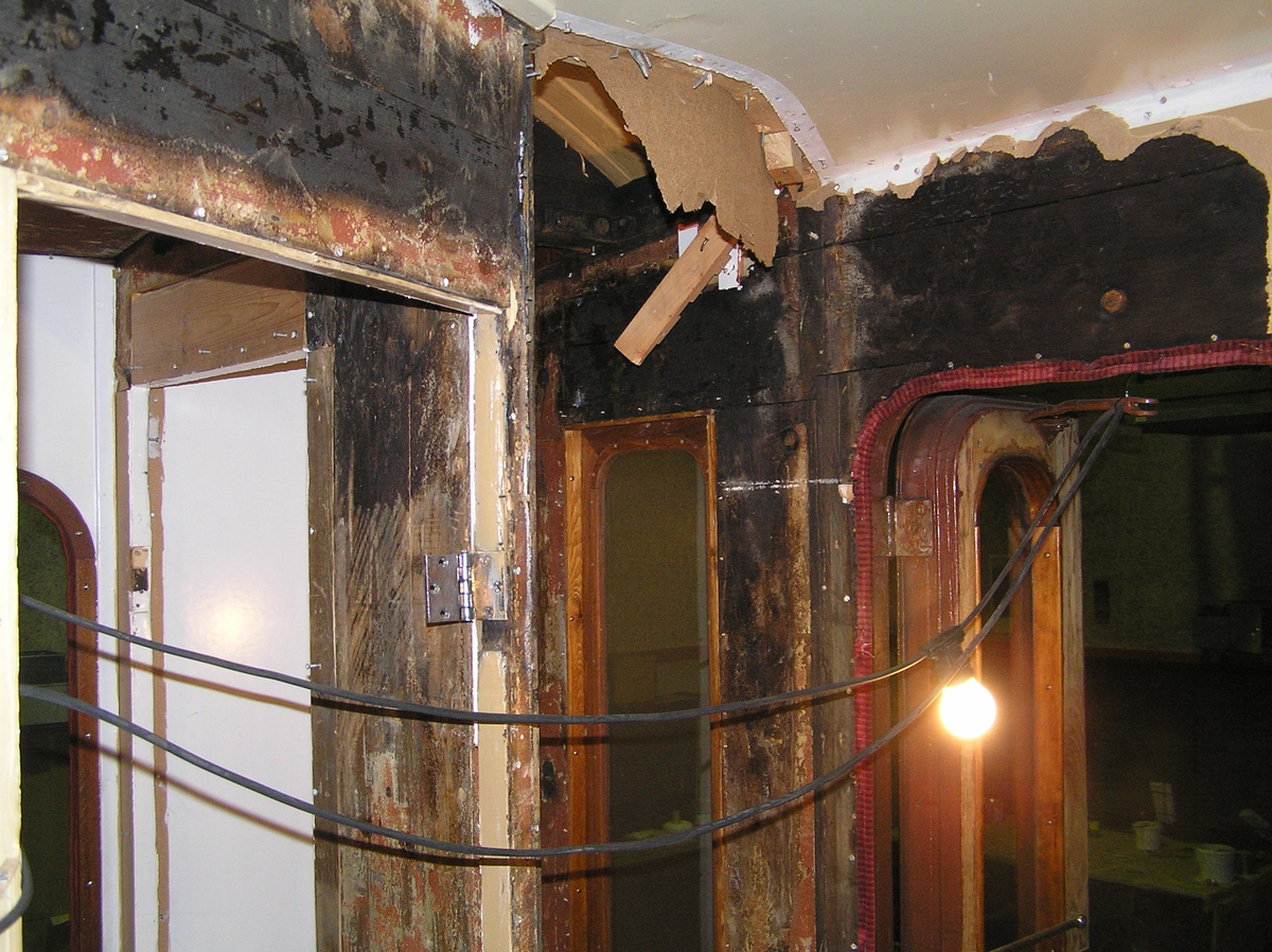 Del av brandhärjad vägg och tak i vestibul i SJ Ro2 2702 innan demontering. Inrymde tidigare toalett men är nu teknikrum.