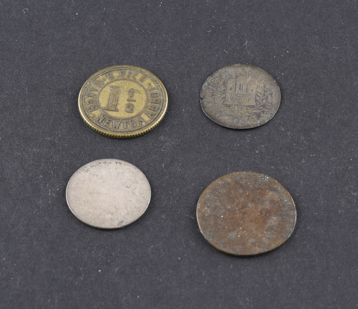 Fire mynter og polletter i varierende størrelse og tilstand. Myntene er fra USA, Tyskland og England. Myntene og polettene var oppbevart i en liten papirpose.
