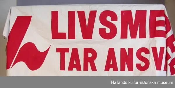 Banderoll av oblekt bomullsväv med röd, målad text: "LIVSMEDELSFACKET TAR ANSVAR FÖR DIN MAT".