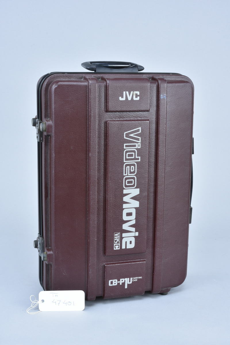 Videokamera med mikrofon och inbyggd videobandspelare för VHS-C. JVC typ GR-C1E "Video Movie", nr 110G3400.
I väska typ CB-P1U med tillhörande utrustning:
Sökare KM10057294. Batteri mod NB-P6U på 9,6 V 700 mAh. Batteriladdare JVC BB-P1EG nr 13950061 för anslutning till 110-240 V 50/60 Hz, 20 W förbrukning, 9,6 V 0,8 A = ut. RF-enhet JVC typ RF-P1U, omkopplingsbar mellan kanal 3/4. Videokablar med SCART resp. koaxialanslutning. Strömmatningssladd för 9 V=.