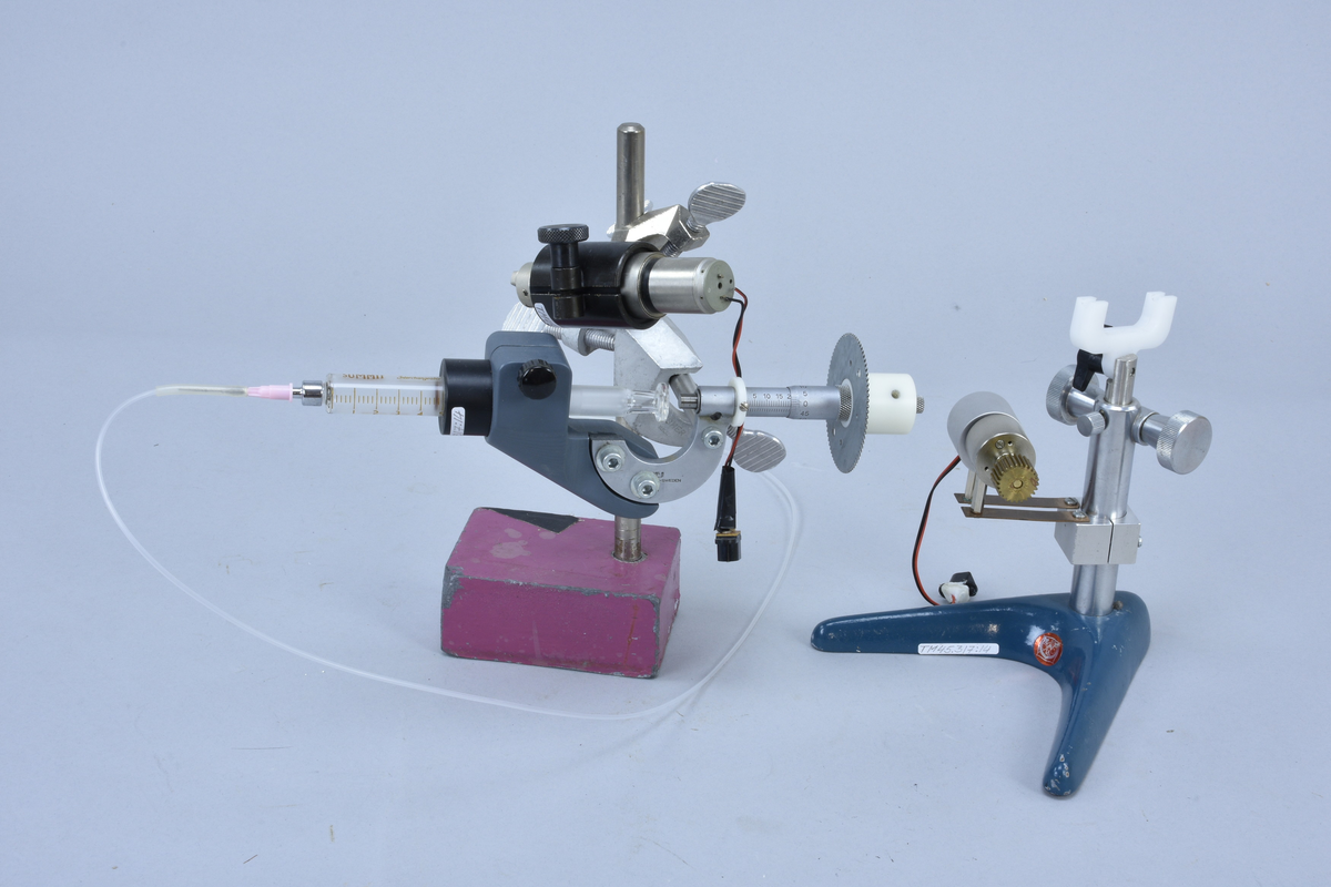 Spruta Narishige IM-6 med frammatningsanordning, för portonering av vätska via slang till petriskål i klimatkammare. Modifierad av Lorentzen Instrumentfirma AB för motordrift, motor på stativ.