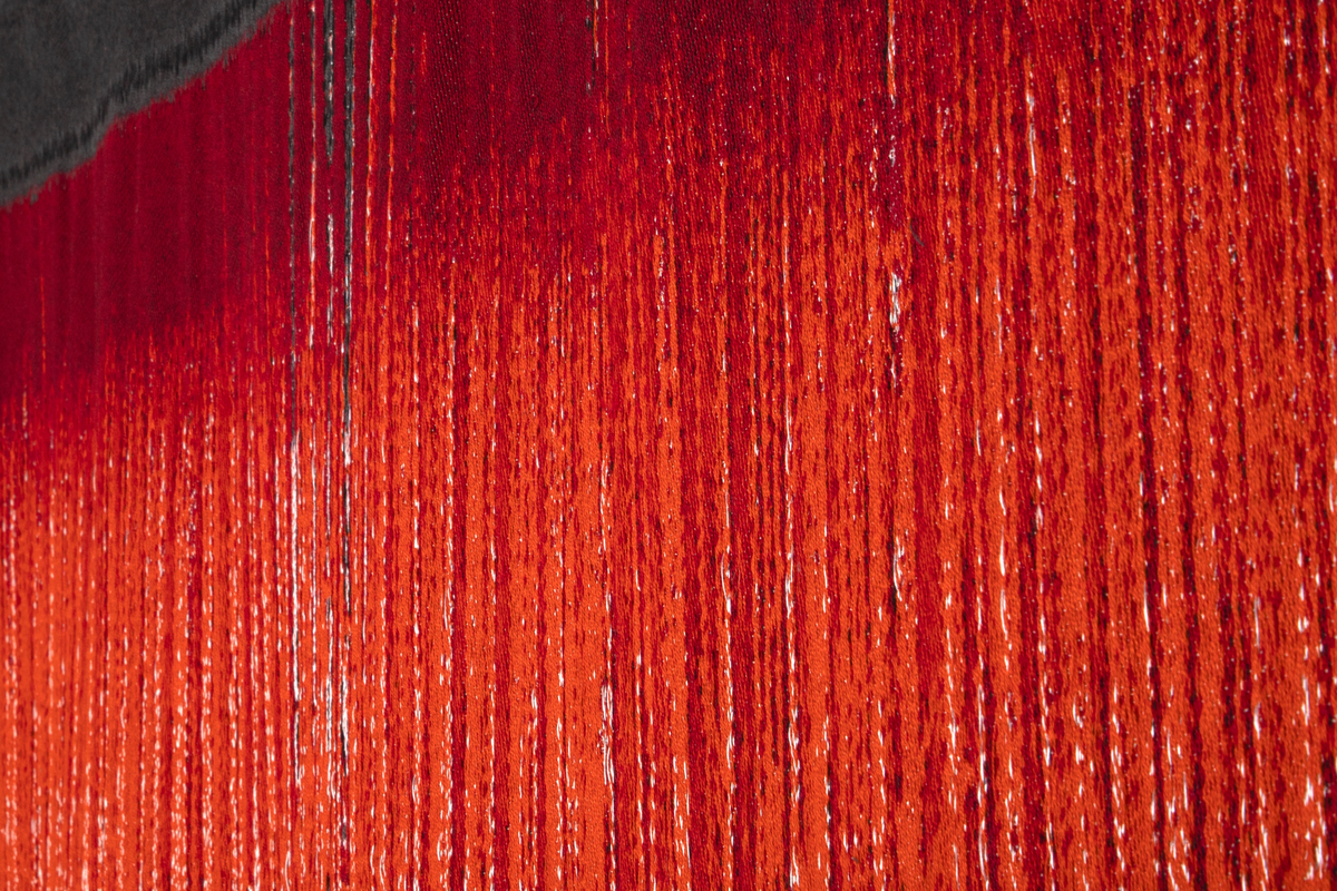 Digitalt vevd veggteppe med ulike nyanser av rødt, flankert av mørk grå (gråbrun). Teppet viser veven slik den ser ut for den som vever, når vedkommende ser ned, ifølge kunstneren. Et rødt teppe som blir vevd, med de løse trådene hengende ned, mot en mørk bakgrunn.