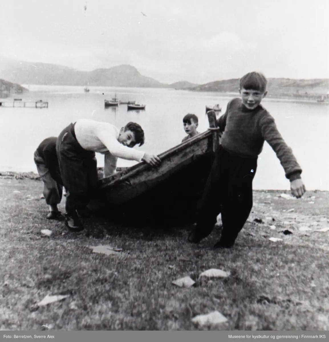 Skoleinternatet i Repvåg. Flere gutter drar en små robåt i fjæra. Høsten 1952.