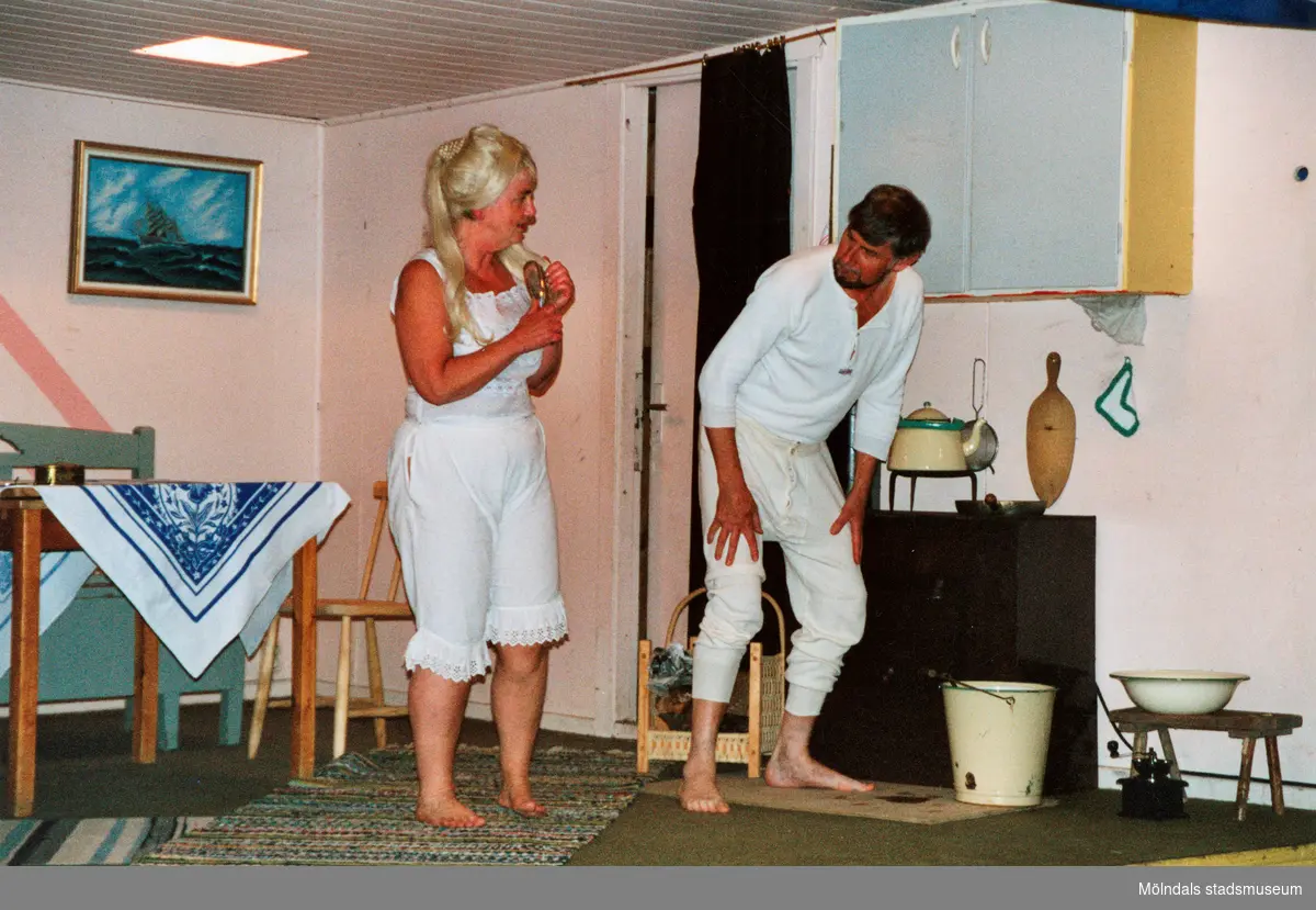Föreställningen "Äggbekymmer & kontaktannons" i Teaterhuset 2001. En köksmiljö där en kvinna och en man står klädda i sina "gammaldags" underkläder.