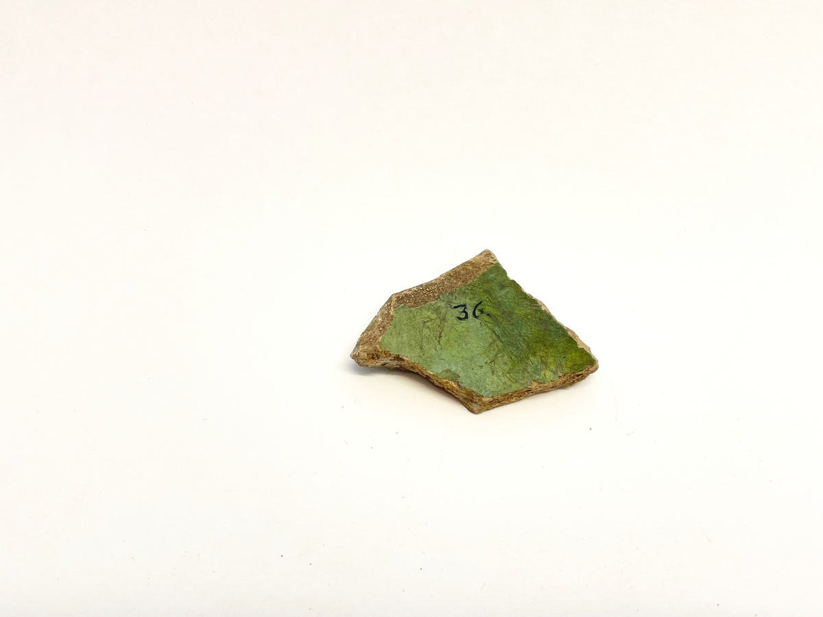 Keramikfragment av ljusrött lergods med grön glasyr på in- och utsidan. Ljusbrännande rödgods eller vitgods? Mycket lik M 48845-26e, 29, 33. 35, 36, 44-49, 68 och 84 i glasyr och gods.
