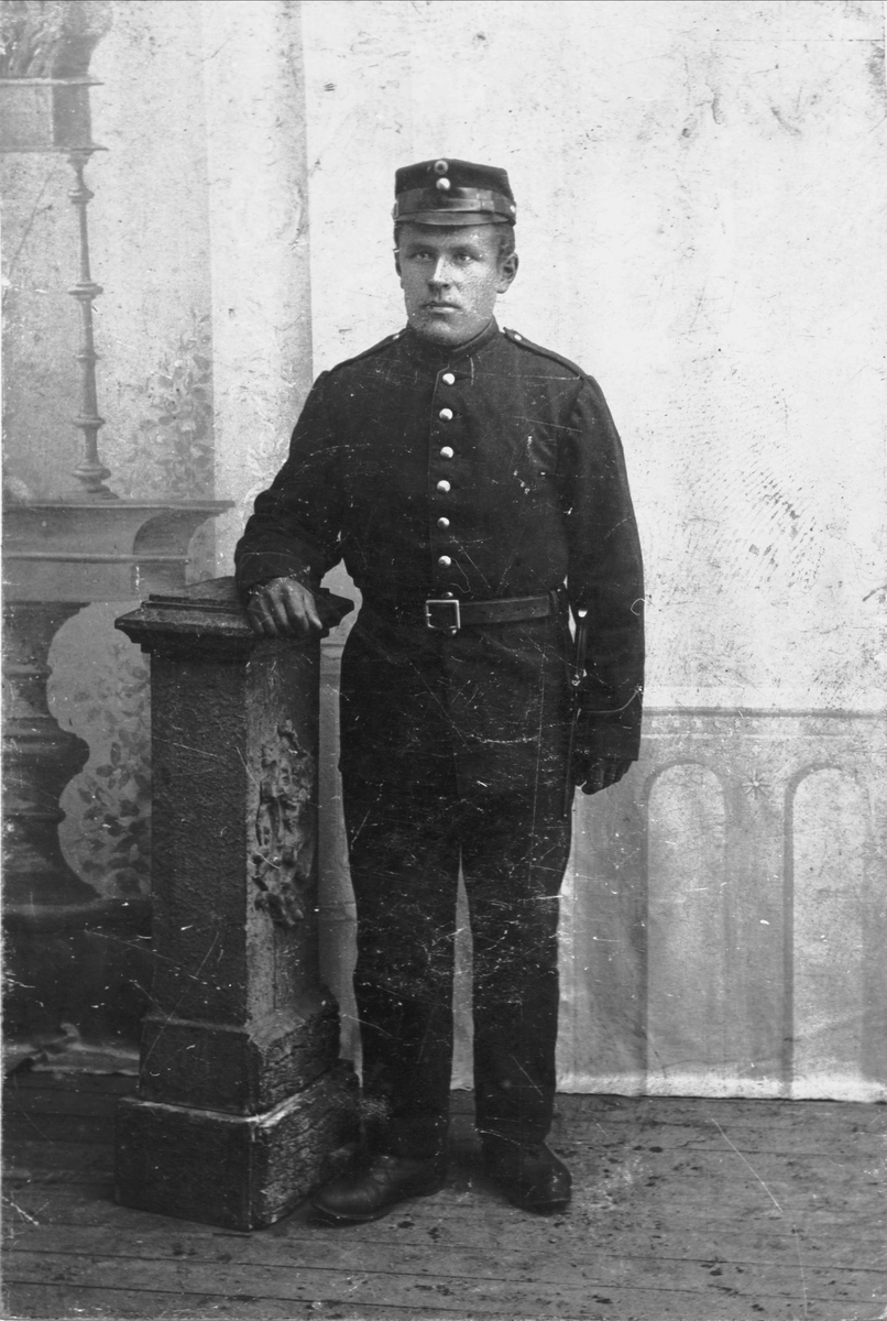 Studioportrett av en soldat, fotografert stående ved en pidestall.
