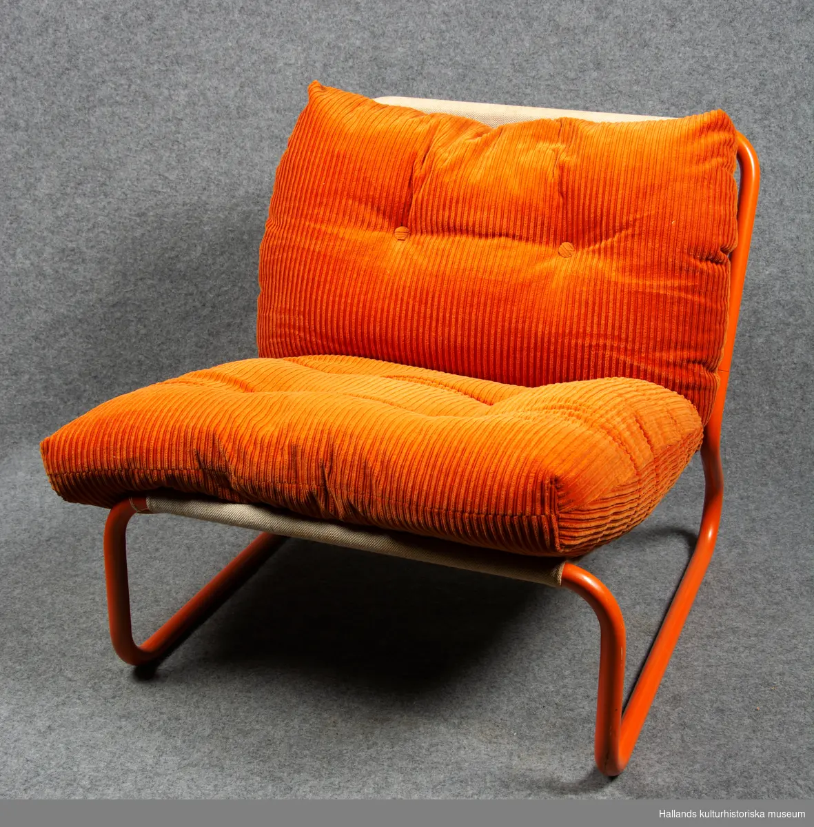 Orangemålat stålrörsstativ med kanvas. Lös, orange manchesterdyna.