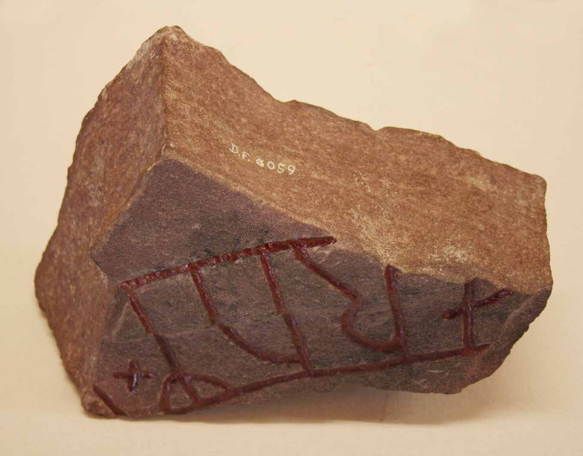 Runstensfragment av rödaktig kvartsitisk sandsten. 
Runornas storlek är 95 mm. Ristningen är djup och tydlig. Inskrift: ....orum x 5. 
Fragmentets baksida har tydliga slingor. Runformer och huggningsteknik ge vid handen att fragmentet tillhör 1000-talet.