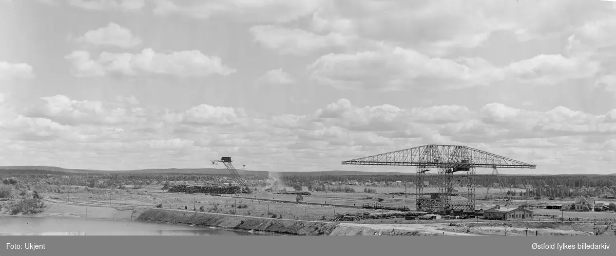 Kran for opptak av sagtømmer og tømmerlager og luftbane til Borregaard fabrikker, Opsund i Sarpsborg 1944. Bildet viser at det var sparsomme tømmerlager under 2. verdenskrig.