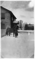 Marie Sandberg gm Karl Larsen holder en hest foran hovedbygn