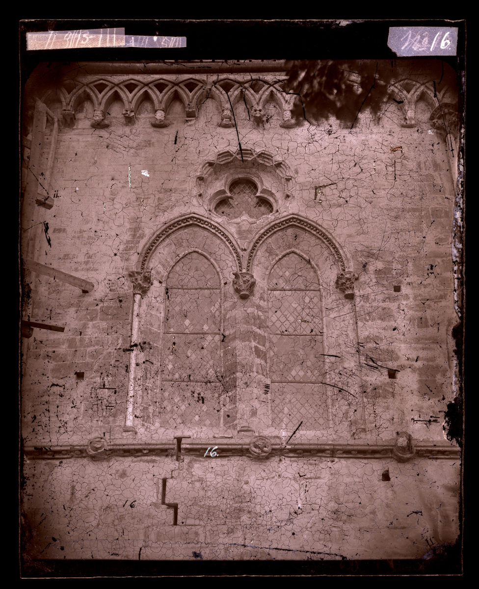 Oktogonens vegg mot nord-øst, med gamle blyglassvindu og middelalderskulptur. Buegesims med konsoller.
Bildet er tatt før restaurering (oktogonen ble restaurert i perioden 1872-1877).