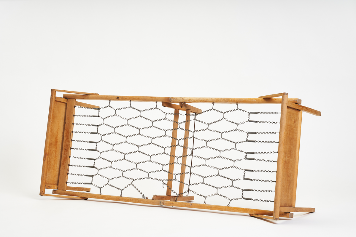 Sammenleggbar seng i lakkert treverk med sengebunn av sammenkoblede metallkjeder.