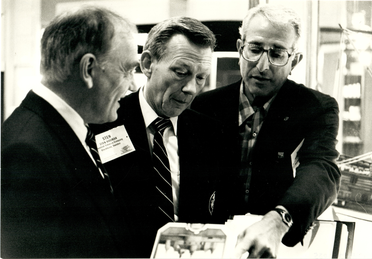 Sten Hagman, från Svenska Tobaksbolaget, i konversation med två andra herrar vid en cigarrmässa.

