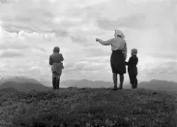 En kvinne med to barn speider utover mot fjellene. Det er uk