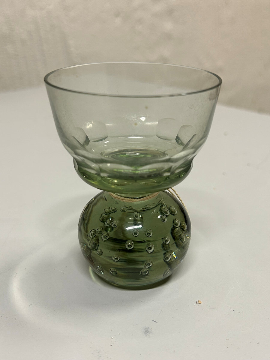 Dricksglas med gröntonat glas. Klotformad fot med luftblåsor. Kupa med olivslipad dekorbård.