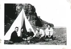En gruppe mennesker sitter rundt et hvitt telt på en slette 