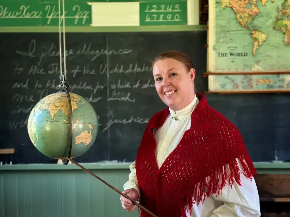 Ny lærer  ønsker barnefamilier velkommen til skolestua på Norsk utvandrermuseum i sommer.