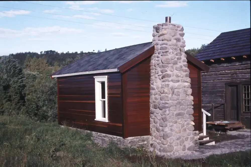 Lite brunt hus med svær skorstein murt i stein på eine kortveggen