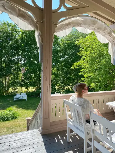 En jente sitter på verandaen på Kvinnemuseet. Det er en fin sommerdag.