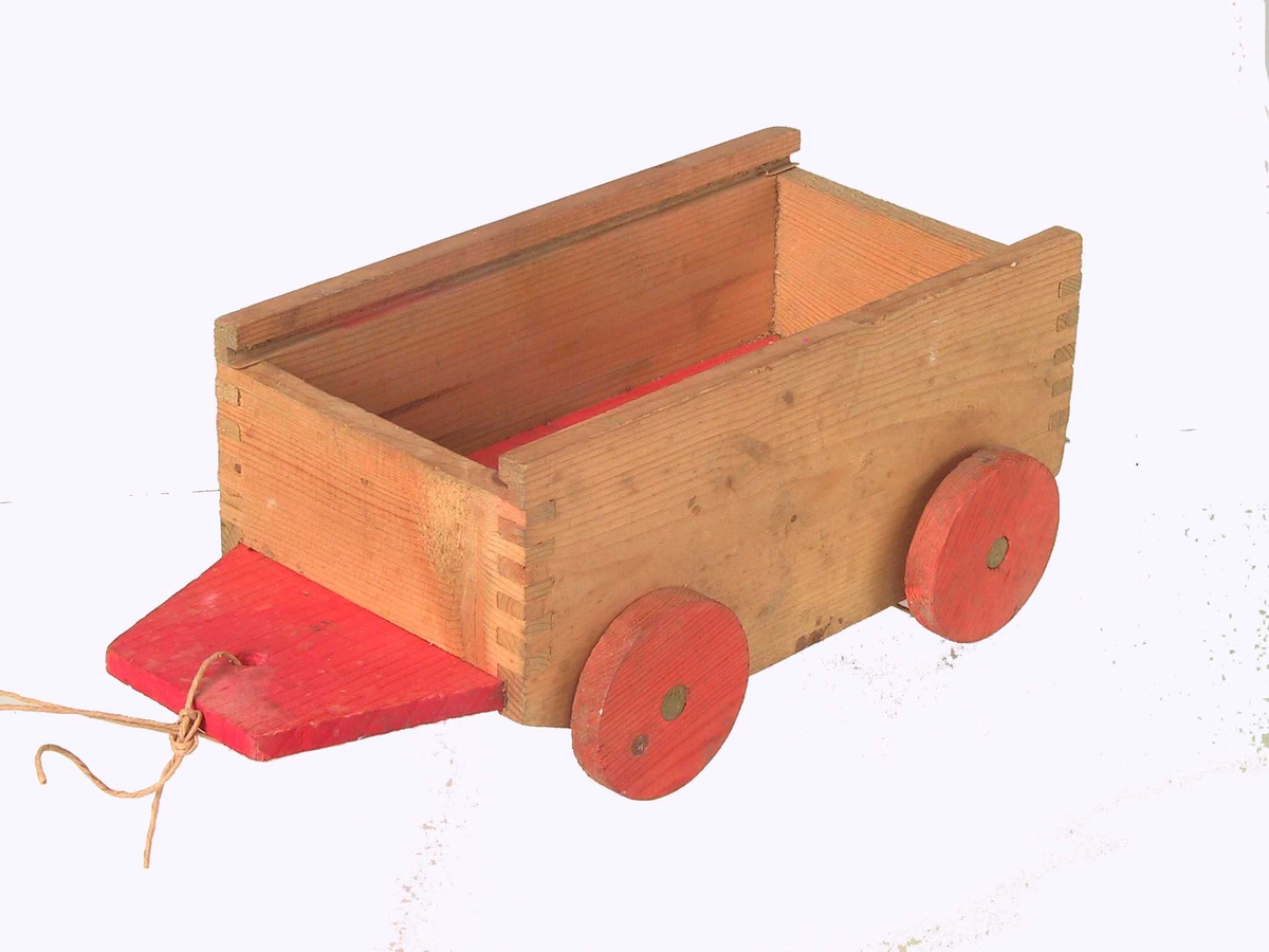 Form: Liten vogn/henger med 4 hjul, har trolig hatt skyvelokk. Bunnen stikker frem foran sideveggene foran, har et hull som det er festet en hyssing gjennom.
