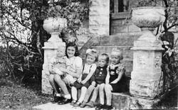 Flere barn på steintrapp med søyler og originale blomsterurn