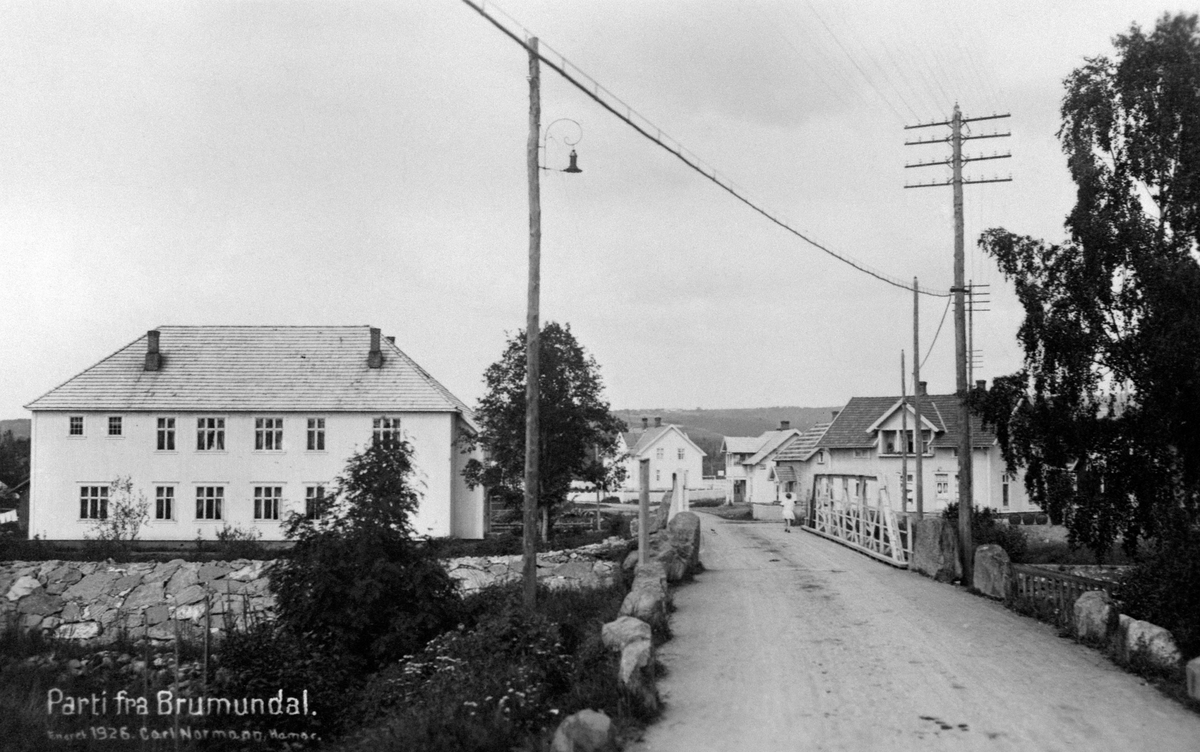 Oversikt Furnesvegen, Brumunddal, brua over Brumunda. Fra venstre er Folkets hus bygd 1922, Pihl, Fredheim, Midtheim (Skalmerud kafe), Stensgård.