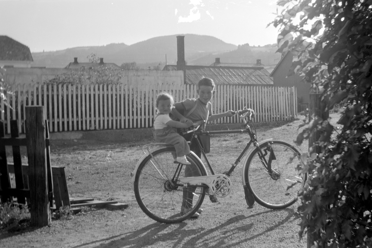 Mordal i Nygata 21 i Brumunddal.  Svein-Erik Mordal f. 1941 med Vilde Kari Mordal f. 1952 på bagasjebrettet. Sykkel. 